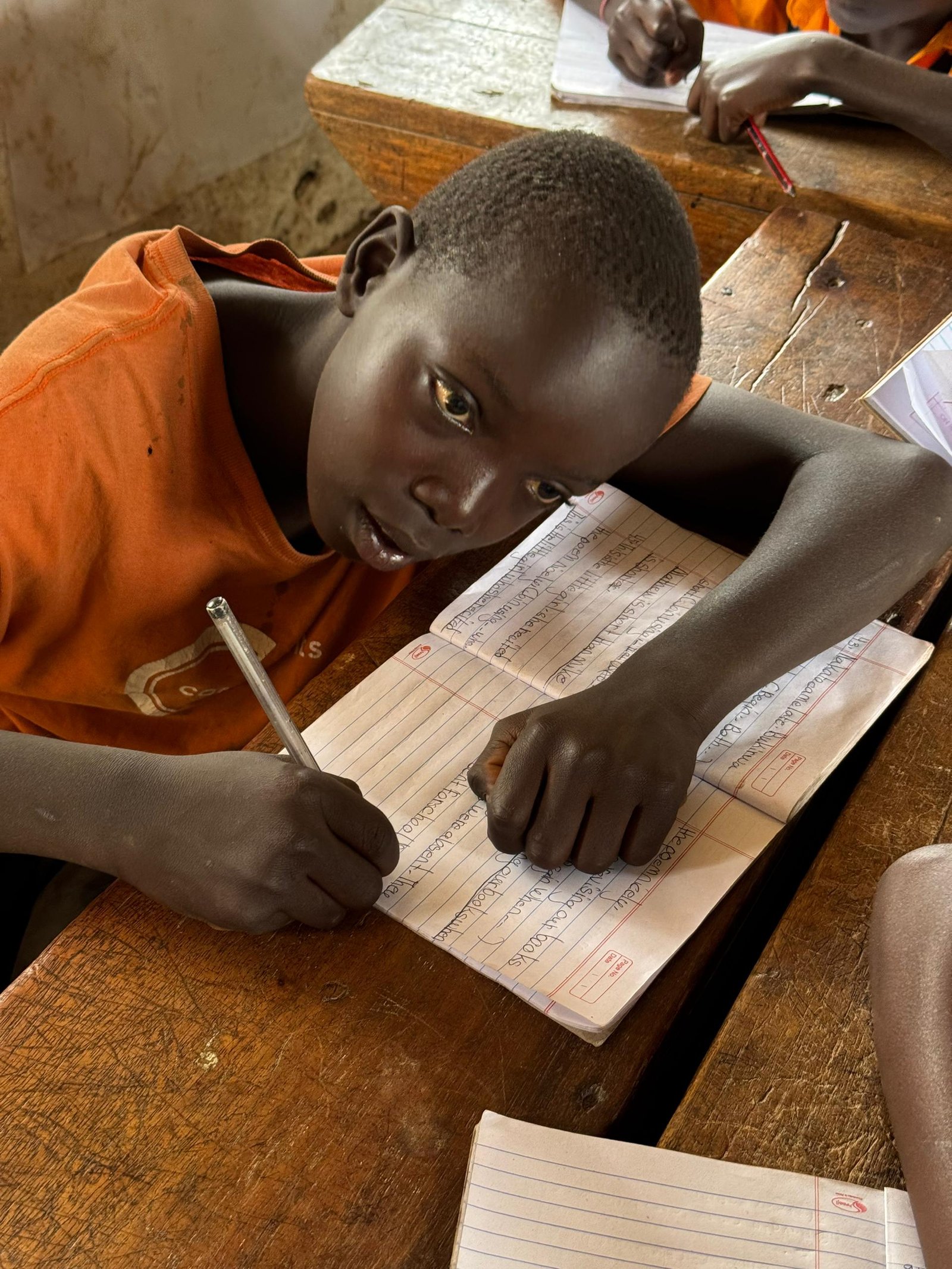 Joseph, a 10-year-old boy reading a book outdoors with a joyful expression